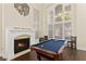A game room offers a pool table, a fireplace, tall windows, and a decorative art piece on the wall at 9517 Spanish Steps Ln, Las Vegas, NV 89117