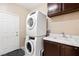 Functional laundry area with stacked washer/dryer, utility sink, and storage, creating an efficient space at 9517 Spanish Steps Ln, Las Vegas, NV 89117