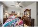 A well-lit bedroom with a ceiling fan, a dresser with mirror, and floral bedding at 11322 Corsica Mist Ave, Las Vegas, NV 89135