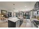 An open kitchen featuring an island with a sink and stainless steel appliances, seamlessly flowing into the living area at 11322 Corsica Mist Ave, Las Vegas, NV 89135