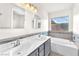 Bathroom featuring double sinks, a soaking tub, and a large window for natural light at 2151 Babylon Mill St, Henderson, NV 89002