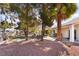 A well-maintained backyard with mature trees providing shade and a cozy seating area on a brick patio at 2246 Cassatt Dr, Henderson, NV 89074