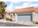 Home exterior with a tile roof, neutral stucco, gray garage door, complemented by manicured landscaping at 2246 Cassatt Dr, Henderson, NV 89074