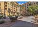 Beautiful courtyard featuring lush landscaping, an outdoor fireplace, and seating areas amidst the building's architecture at 2405 W Serene Ave # 817, Las Vegas, NV 89123