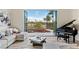 Bright living room featuring a baby grand piano, stylish furnishings, and an outdoor view of a jacuzzi at 2436 Grassy Spring Pl, Las Vegas, NV 89135