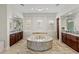 Bright primary bathroom showcasing a marble-surround tub, dual vanities, and tile floors at 2436 Grassy Spring Pl, Las Vegas, NV 89135