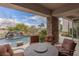 Inviting covered patio featuring a stone pillar, stylish seating, and a serene view of the pool with a waterfall feature at 2436 Grassy Spring Pl, Las Vegas, NV 89135