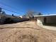 View of spacious backyard with mature tree, partial block wall, and covered patio at 5129 Sugarfoot Ave, Las Vegas, NV 89107