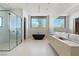 Contemporary bathroom boasts dual sinks, soaking tub, and walk-in shower with expansive backyard views at 63 Midnight Sky Dr, Las Vegas, NV 89135