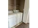 Functional laundry area with stacked washer and dryer, overhead shelving, and tile flooring at 6608 Elk Creek Ln, Las Vegas, NV 89156