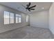Bright bedroom featuring plush carpeting, a ceiling fan, and multiple windows for ample natural light at 6630 Windy Palm St, North Las Vegas, NV 89086