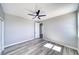 Minimalist bedroom with wood-look floors, ceiling fan, and natural light at 6631 S Parkwood Ct, Pahrump, NV 89061