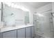 Modern bathroom featuring a double vanity, large mirror, and glass-enclosed shower at 6925 Cuddy Falls Pl, North Las Vegas, NV 89084