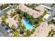 Aerial view of a desert community with a uniquely shaped pool, lush trees, and well maintained roofs at 7155 S Durango Dr # 303, Las Vegas, NV 89113