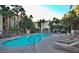 Inviting outdoor pool with lounge chairs, towering palm trees, and a lush landscaping at 7155 S Durango Dr # 303, Las Vegas, NV 89113