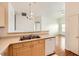 This cozy kitchen features a dishwasher, double sinks, wood cabinets and an open view to the living room at 8787 Roping Rodeo Ave # 101, Las Vegas, NV 89178