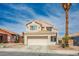 Two-story home featuring a two-car garage, desert landscaping and a beige stucco exterior at 938 Carnival Ave, Las Vegas, NV 89123