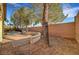 Wide shot of backyard featuring a curved stone wall, mature trees, and brick perimeter wall at 9485 Parkmoor Ave, Las Vegas, NV 89149
