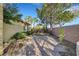 Backyard view featuring desert landscaping, mature trees, brick wall, and concrete pavers at 9485 Parkmoor Ave, Las Vegas, NV 89149