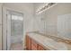 Bathroom featuring double sinks, granite countertops, a large mirror, and a tiled bath and shower at 9485 Parkmoor Ave, Las Vegas, NV 89149