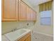Bright laundry room featuring lots of cabinets, a sink, tile flooring, and natural light from the window at 9485 Parkmoor Ave, Las Vegas, NV 89149