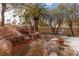 Backyard view showcasing a rock waterfall, fire pit seating area, and mature trees for privacy and shade at 21 Ocean Harbour Ln, Las Vegas, NV 89148
