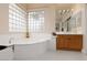 Bright bathroom featuring a soaking tub, a window of glass blocks, and a vanity with wooden cabinets at 21 Ocean Harbour Ln, Las Vegas, NV 89148