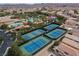 Aerial view showcasing well-maintained tennis courts with a dark green surround nestled in a residential community at 21 Ocean Harbour Ln, Las Vegas, NV 89148