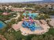 Aerial view of a community waterpark with slides, a pool, and lounge chairs surrounded by palm trees and lush landscaping at 21 Ocean Harbour Ln, Las Vegas, NV 89148