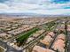 A high aerial showcases a community with green spaces, swimming pool, and sports courts, set against a mountain view at 2376 Via Firenze, Henderson, NV 89044