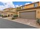 A street view of townhomes featuring desert landscaping and private two-car garages at 2376 Via Firenze, Henderson, NV 89044
