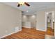 Open living room with wood floors, ceiling fan, and access to hallway and bathroom at 2376 Via Firenze, Henderson, NV 89044