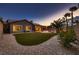Spacious backyard featuring an artificial lawn, desert landscaping, and covered patio with sunset views at 2764 Kilwinning Dr, Henderson, NV 89044