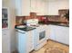 Well-lit kitchen features white cabinets and appliances, black countertops, decorative backsplash and tiled floor at 6412 Big Pine Way, Las Vegas, NV 89108