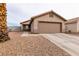 Front exterior of home with tan stucco, two-car garage, and low-maintenance desert landscaping at 652 Carlos Julio Ave, North Las Vegas, NV 89031