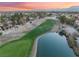 Scenic aerial view of a golf course with a pond surrounded by lush greenery and beautiful sunset skies at 7608 Painted Dunes Dr, Las Vegas, NV 89149