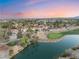 An aerial view of a golf course community with multiple red-tile-roof homes around a pond at 7608 Painted Dunes Dr, Las Vegas, NV 89149