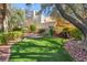 Serene backyard with artificial turf, mature trees, and a tranquil water feature at 7608 Painted Dunes Dr, Las Vegas, NV 89149