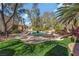 Lush backyard featuring a pool, spa, mature trees, and green artificial turf, perfect for outdoor living at 7608 Painted Dunes Dr, Las Vegas, NV 89149