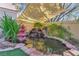 A beautiful garden pond with a waterfall and koi fish, surrounded by lush greenery and decorative stones at 7608 Painted Dunes Dr, Las Vegas, NV 89149