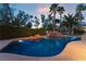 Inviting pool with rock waterfall feature, surrounded by lush landscaping and palm trees at dusk at 7608 Painted Dunes Dr, Las Vegas, NV 89149