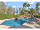 Inviting pool with rock waterfall feature surrounded by lush landscaping and mature palm trees at 7608 Painted Dunes Dr, Las Vegas, NV 89149