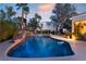 Beautiful pool with rock waterfall features and lush tropical landscaping creating a backyard paradise at 7608 Painted Dunes Dr, Las Vegas, NV 89149