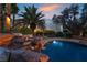 Relaxing pool area with rock features and lush palm trees, perfect for enjoying the desert sunset at 7608 Painted Dunes Dr, Las Vegas, NV 89149