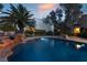 Backyard pool with a rock waterfall feature, surrounded by lush palm trees and desert landscaping at 7608 Painted Dunes Dr, Las Vegas, NV 89149