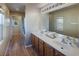 Bathroom with a dual sink vanity, large mirror and wood-style flooring at 7731 Ornamento Way, Las Vegas, NV 89179