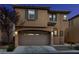 Inviting two-story home featuring a neutral color scheme, arched garage door, and well-maintained landscaping at dusk at 7731 Ornamento Way, Las Vegas, NV 89179