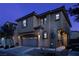 Two-story home with an attached garage, showcasing the front facade, landscaping, and exterior lighting at dusk at 7731 Ornamento Way, Las Vegas, NV 89179