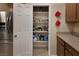 Spacious pantry with shelves, next to stainless steel refrigerator in kitchen at 7731 Ornamento Way, Las Vegas, NV 89179