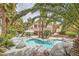Backyard pool and patio area surrounded by tropical plants and mature palm trees at 8324 Slate Harbor Cir, Las Vegas, NV 89128